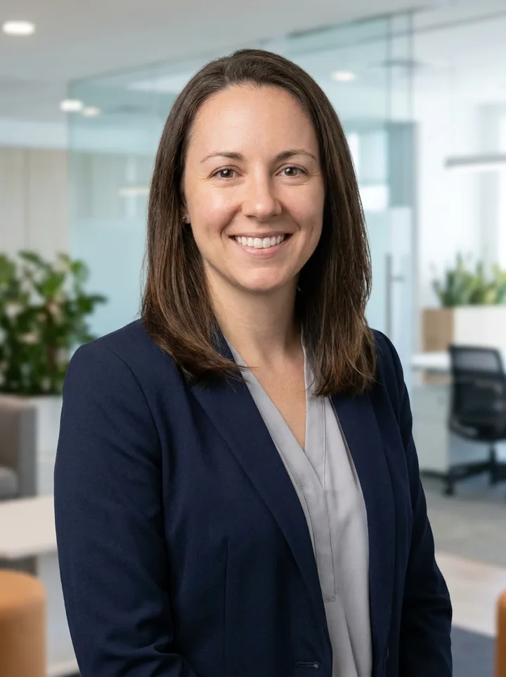 The same woman as a professional headshot in a navy blazer with a blurred office background
