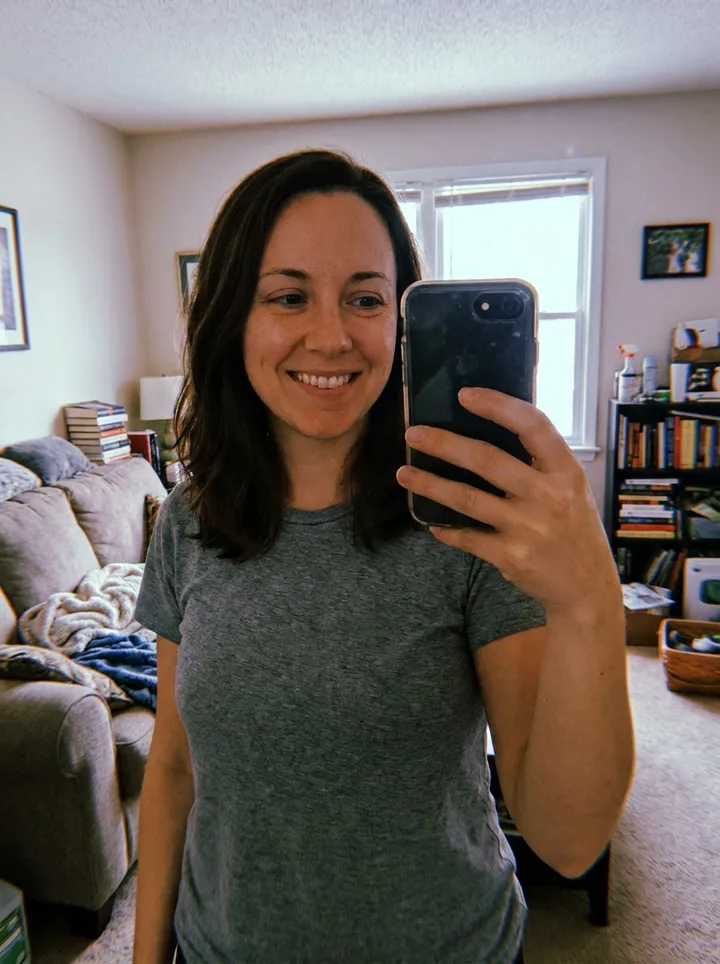Casual mirror selfie of a woman in a t-shirt in her living room