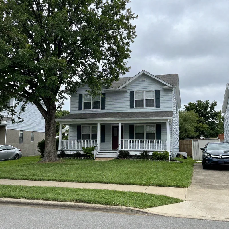 Original photo of a two-story house with a porch, a tree and a parked car